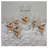 Pitcher with 5 glasses.  These items are likely produced by the "West Virginia Glass" likely from the mid-century era, featuring a distinctive pheasant-in-flight design with gold rim embellishments.