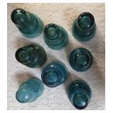 Eight Vintage electric line insulators most likely produced by the Hemingray Glass Company.  Aqua-blue color is characteristic of early 20th century glass manufacturing.