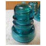 Eight Vintage electric line insulators most likely produced by the Hemingray Glass Company.  Aqua-blue color is characteristic of early 20th century glass manufacturing.