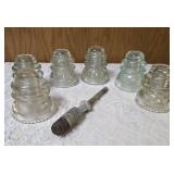Six vintage clear glass insulators, specifically resembling the Hemingray-45 model based on their shape and color and a pin glass insulator.