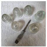 Six vintage clear glass insulators, specifically resembling the Hemingray-45 model based on their shape and color and a pin glass insulator.