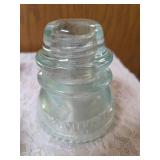 Six vintage clear glass insulators, specifically resembling the Hemingray-45 model based on their shape and color and a pin glass insulator.