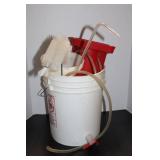Red Plastic Fluid Pump with Clear Tubing and Cleaning Brush in Bucket
