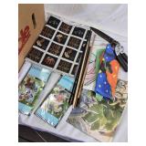 Box of Home and Garden Decor Items Including Decorative Flags, Artificial Flowers, Fabric, and Garden Tools