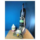 This upright cleaning machine is a Hoover Max Extract 60 Pressure Pro Carpet Deep Cleaner (Model FH50220). It is pictured next to a multi-purpose carpet cleaning formula