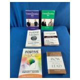 Collection of six self-improvement, financial literacy, leadership, and communication books laid out on a blue fabric surface.
