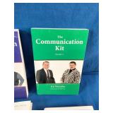 Collection of six self-improvement, financial literacy, leadership, and communication books laid out on a blue fabric surface.