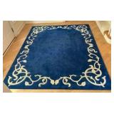 Blue area rug with distinctive cream-colored floral border pattern
