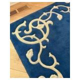 Blue area rug with distinctive cream-colored floral border pattern