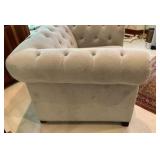 Cream colored velvet armchair with deep-button tufting and rolled arms