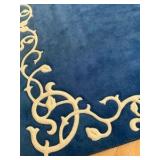 Blue area rug with distinctive cream-colored floral border pattern