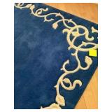 Blue area rug with distinctive cream-colored floral border pattern