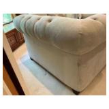 Cream colored velvet armchair with deep-button tufting and rolled arms