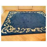 Blue area rug with distinctive cream-colored floral border pattern