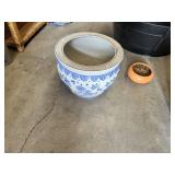 Plastic, ceramic, and metal planters including large black plastic tub and decorative blue and white ceramic pot with additional containers