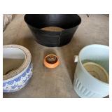 Plastic, ceramic, and metal planters including large black plastic tub and decorative blue and white ceramic pot with additional containers