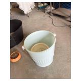 Plastic, ceramic, and metal planters including large black plastic tub and decorative blue and white ceramic pot with additional containers