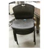 Four black plastic stacking chairs