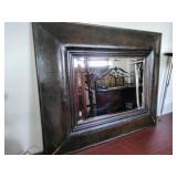 Accent wall mirror features a heavy, dark-finished frame that resembles faux leather