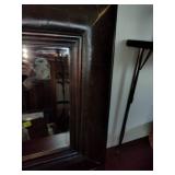 Accent wall mirror features a heavy, dark-finished frame that resembles faux leather