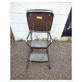 This is a vintage Mid-Century Modern Cosco kitchen step stool featuring a brown flip-up seat and chrome frame.