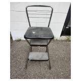 This is a vintage Mid-Century Modern Cosco kitchen step stool featuring a brown flip-up seat and chrome frame.