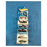 Stack of six carded Hot Wheels die-cast cars packaged from the late 1990s through the mid-2000s.