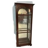 Arched curio cabinet with a walnut finish and a mi