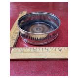 Silver plate stand holding a wooden coaster
