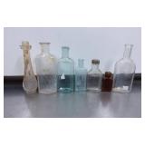 Seven Vintage Glass Bottles in Various Shapes and