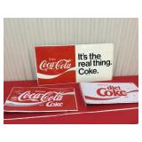 Three metal Coca-Cola signs