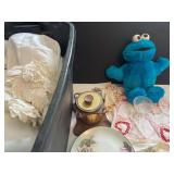 PLASTIC TOTE CONTAINING LINENS, QUARTZEX STEMMED GOBLETS—2 WITH ORIGINAL PAPER LABELS AND ADDITIONAL WRAPPED GLASSWARE, HUMIDOR, FLORAL-PAINTED PLATE, COOKIE MONSTER FIGURE, ETC.