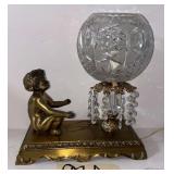 VINTAGE METAL-BASE LAMP WITH CHERUB FIGURE, PRESSED/CUT GLASS GLOBE, AND PRISMS, APPROX. 10.5" WIDE X 11" TALL