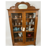 ANTIQUE OAK 5-SHELF BOOKCASE WITH GLASS DOOR, CARVED TOP, AND OVAL BEVELED MIRROR; CONTENTS NOT INCLUDED
