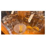 CONTENTS OF BOTTOM SHELF OF CURVED CHINA CABINET: ASSORTED GOLD-TRIMMED GLASSWARE—CREAMER, SUGAR, 3 PITCHERS, 4 TUMBLERS, AND BOWL WITH GOLD-TONE METAL SERVING UTENSILS