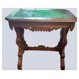 ANTIQUE WALNUT VICTORIAN TABLE WITH ORNATE BASE AND CASTERS; TOP FELT REQUIRES REPLACEMENT
