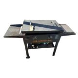 BLACKSTONE 2-BURNER PROPANE FLAT TOP GRIDDLE W/ HOODED COVER, SIDE SHELVES, LOWER STORAGE SHELF, AND WHEELED STAND.