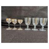 Set of three small glass goblets with painted gold trim and floral design, and set of three clear glass goblets from Sweden