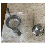 silver-toned metal tea strainer with a single hane