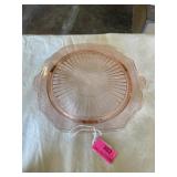 Pink depression glass footed cake plate .