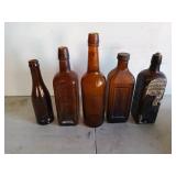 Five Brown glass bottles, one still has some of