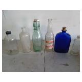 Six glass bottles, one is cobalt blue