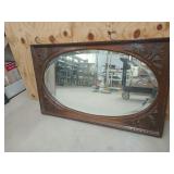 Old oval beveled mirror in ornate wooden frame,