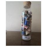 10 in glass bottle full of wooden thread spools .