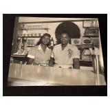 2 Women Posing Behind a Counter