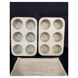 2 stoneware muffin pans with a hot pad