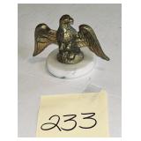 Vintage brass eagle figurine mounted on a white..