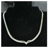 Silver-toned V-shaped tennis necklace featuring..