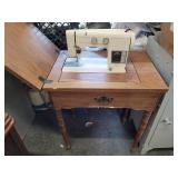 Signature sewing machine in wood cabinet.