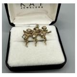 14kt three cherub pendant each holding a round dia
